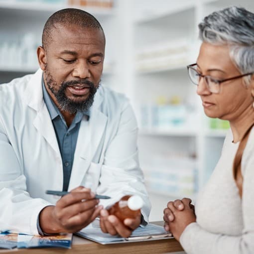 Pharmacy, black man and woman with healthcare medicine and conversation for instructions. Pharmacist, female patient or medical professional talking, stress or explain prescription to senior customer.