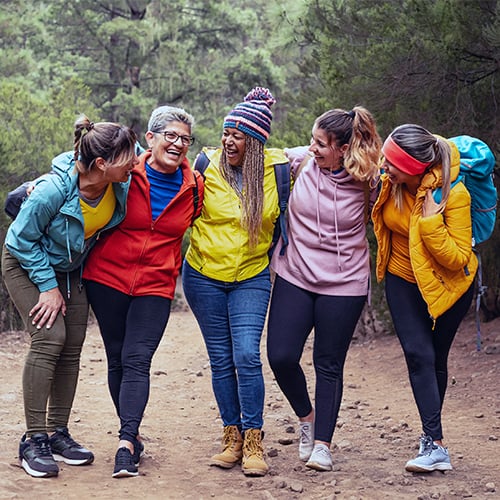 Happy women with different ages and ethnicities having fun walking in the woods, participating in the Come Alive Passport Program.