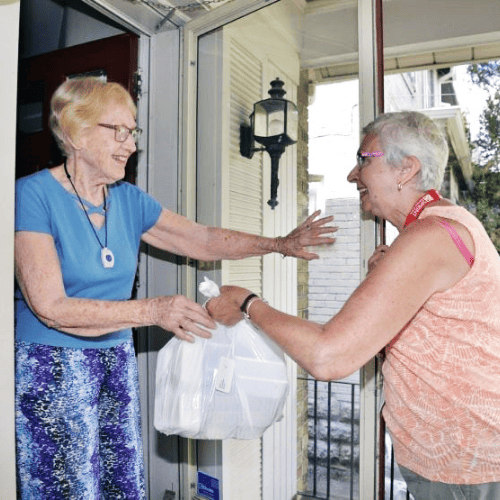 Woman delivering a meal to another woman for the Meals on Wheels program