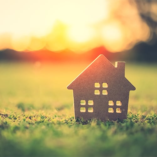 Small model home on green grass with sunlight abstract background. Vintage tone filter effect color style.