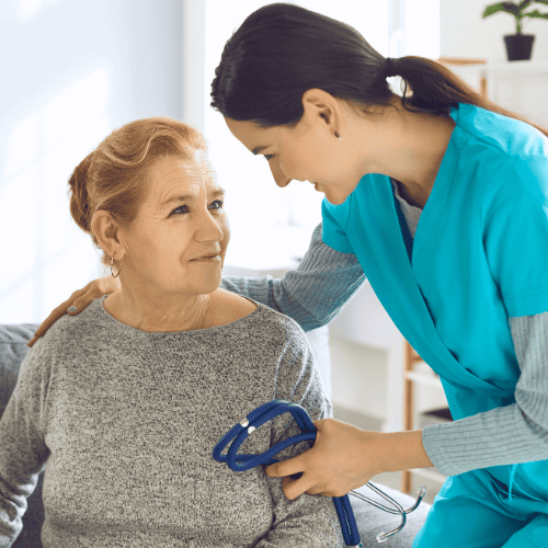 Female health attendant speaking kindly to a patient in exam room.